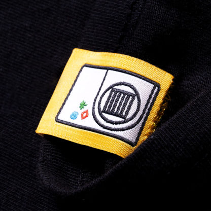 back of a yellow sewn-on tag on a black shirt that says shows an illustrated freeze dryer