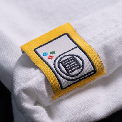 back of a yellow sewn-on tag on a white shirt that says shows an illustrated freeze dryer