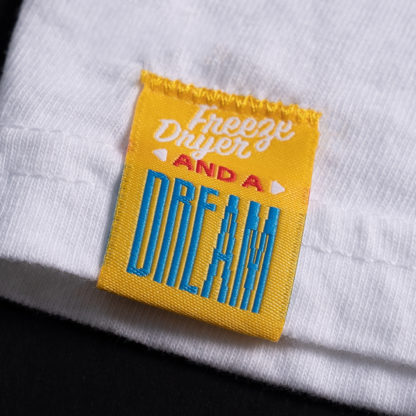 front of a yellow sewn-on tag on a white shirt that says "Freeze Dryer and a Dream"